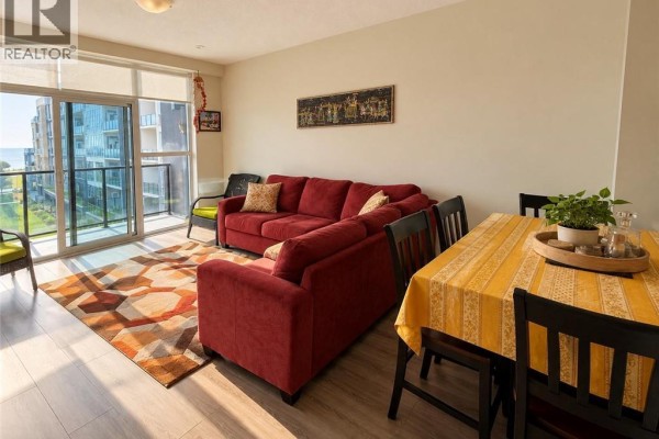 Living and dining area with red sectional sofa, dining table, and floor-to-ceiling window view. - 16 Concord Place Unit# 427, Grimsby