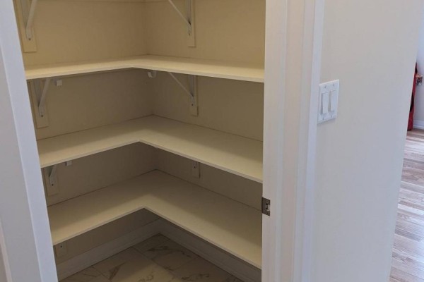 Walk-in corner pantry with multiple white shelves and tiled floor. - 16 Coote Court, Ajax