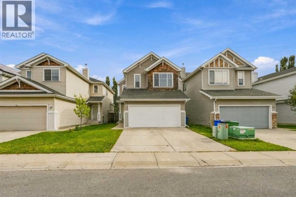 Front exterior view of a two-story house with a double garage and grey siding. - 16 Cougartown Place Sw, Calgary