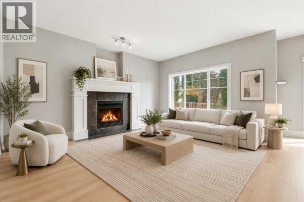 Staged living room with a sofa, armchair, coffee table, and fireplace with mantel. - 16 Cougartown Place Sw, Calgary