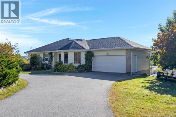 Side view of a beige house with a double garage door and a paved driveway. - 16 Darling Court, Quispamsis