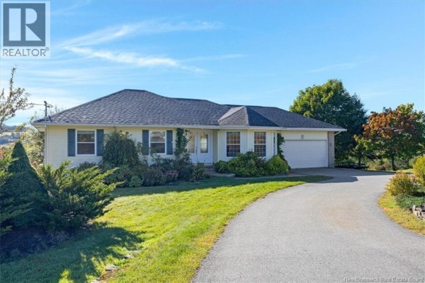 Exterior view of a beige bungalow with a grey roof and lush green landscaping. - 16 Darling Court, Quispamsis