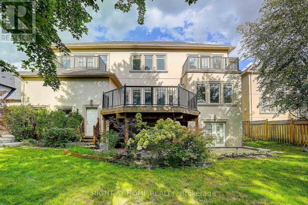 Rear exterior of a house with a wooden deck, multiple balconies, green lawn, and mature trees. - 16 Fairview Avenue, Richmond Hill