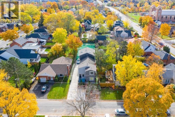 Aerial view of a street with residential homes, mature trees in vibrant fall foliage, and a distant view. - 16 Forest Hill Road, St  Catharines