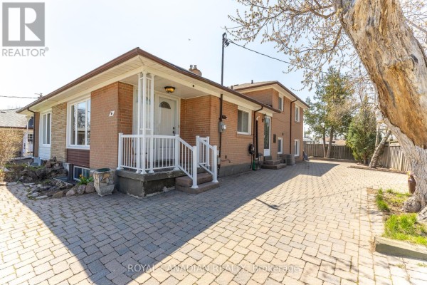 Side exterior of a brick house with a paved driveway and a large tree. - 16 Gambello Crescent, Toronto