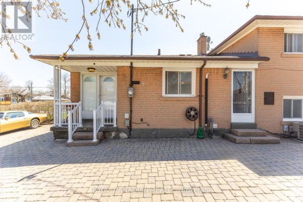 Back exterior of a brick house with two doors and a paved driveway. - 16 Gambello Crescent, Toronto