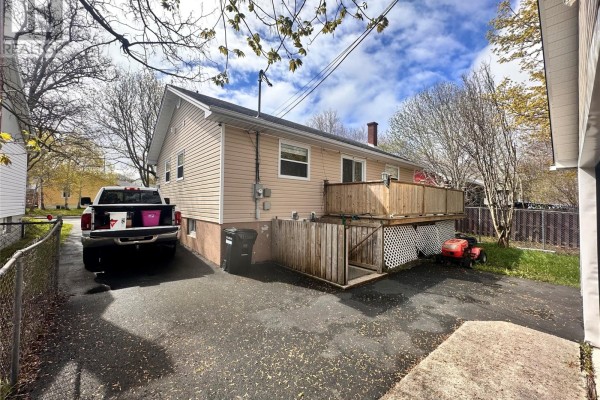 Rear view of a beige bungalow with a wooden deck and fenced yard. - 16 Hatcher Street, St  John S