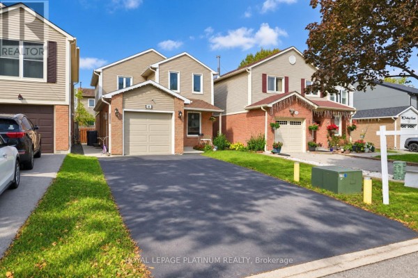 Front exterior of a residential house with a paved driveway, green lawn, and attached garage on a sunny day. - 16 Joshua Court, Brampton