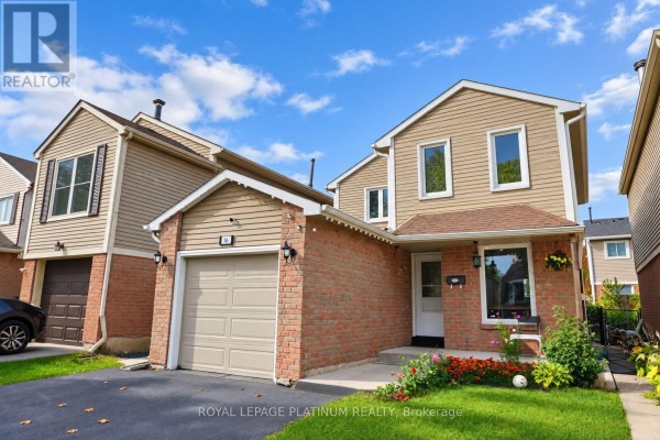Side view of a house showing the beige siding, brick facade, and an attached garage with a beige door. - 16 Joshua Court, Brampton