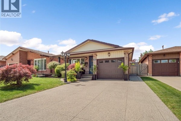 Residential house exterior with a driveway, garage, and mature trees. - 16 Juniper Drive, Stoney Creek