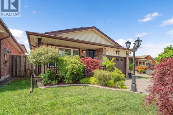 Side exterior view of a residential house with manicured landscaping and a driveway. - 16 Juniper Drive, Stoney Creek