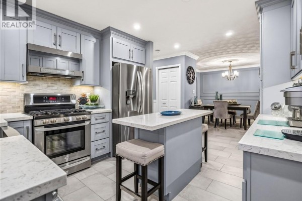 Kitchen and dining area with light blue cabinets, stainless steel appliances, and a chandelier. - 16 Juniper Drive, Stoney Creek