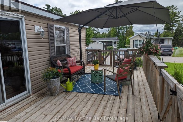 Covered deck with seating area, decorative plants, and outdoor rug. - 16 Kenora Trail, Wasaga Beach