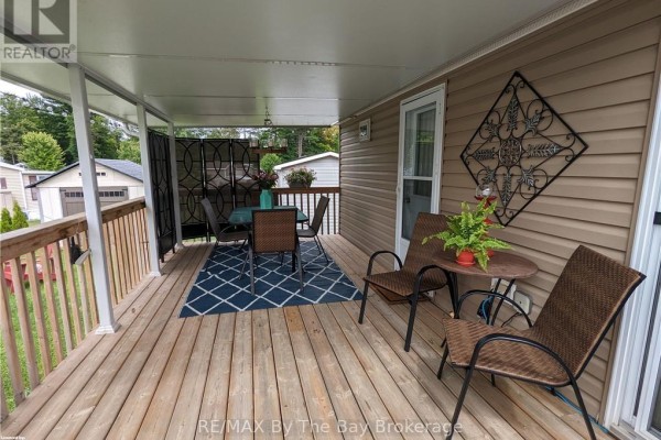 Covered porch with seating and decorative elements, overlooking yard. - 16 Kenora Trail, Wasaga Beach