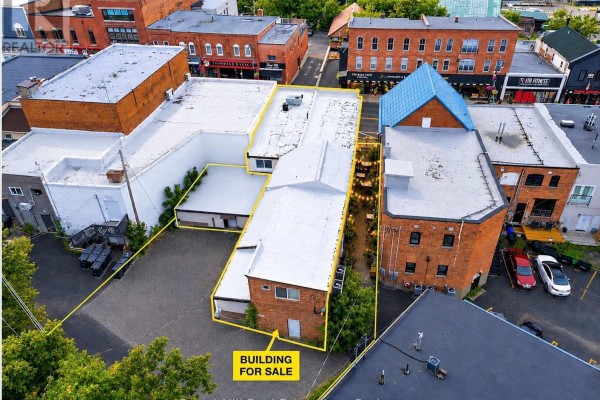 Aerial view of a commercial building complex with surrounding brick buildings and parking areas. - 16 Manitoba Street, Bracebridge)