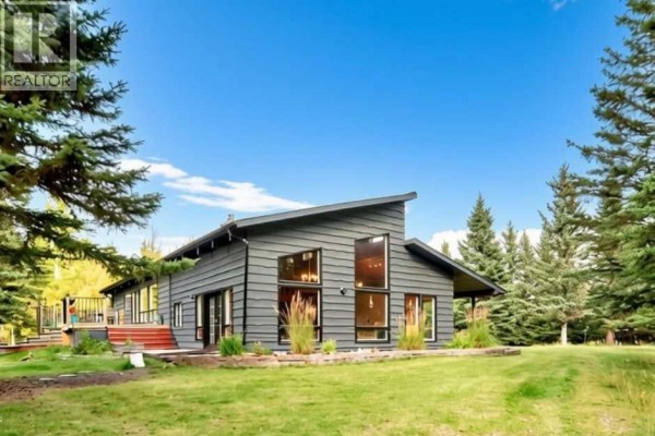 A grey modern house exterior with a sloped roof and large windows. - 16 Mountain View Park, Bragg Creek