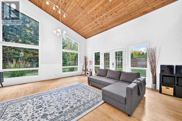 Living room with sectional sofa, patterned rug, and vaulted wood ceiling. - 16 Mountain View Park, Bragg Creek