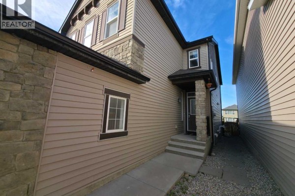 Side view of a house showing the entrance porch with steps and a window. - 16 Nolancrest Green Nw, Calgary