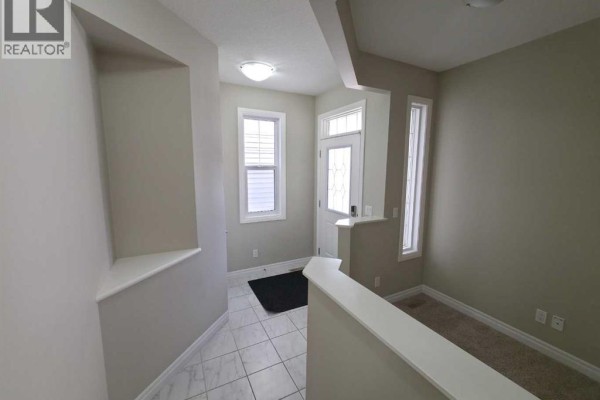 Interior entryway with tiled floor, cream walls, and a door with side windows. - 16 Nolancrest Green Nw, Calgary