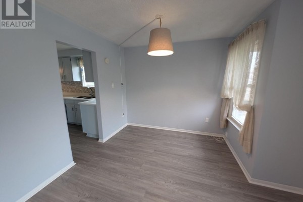 Kitchen area with window, cabinets, sink, and wood-look flooring. - 16 Nortonville Drive, Toronto