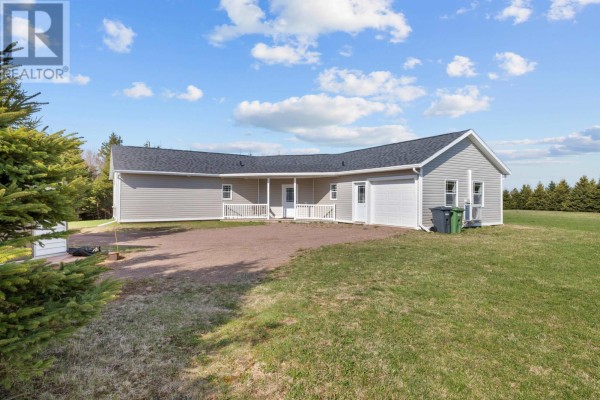 Side view of a gray ranch-style house with a dark roof, showing a white railing, entrance door, and attached garage. - 16 Old Bedford Road Extension, Blooming Point