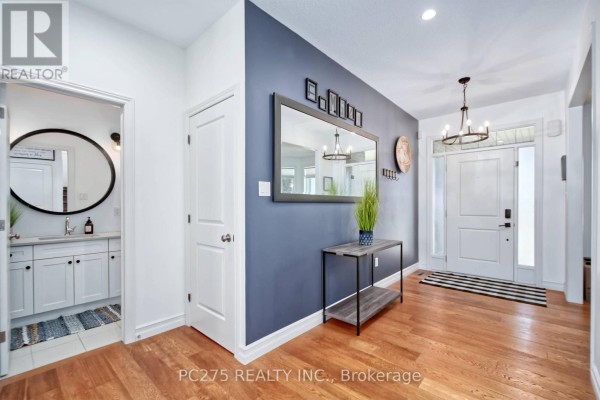 Interior entryway with hardwood floors, blue accent wall, and a staircase. - 16 Peregrine Avenue, Middlesex Centre