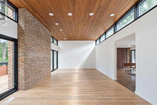 Spacious living room with light wood floors, exposed brick wall, and wood ceiling. - 16 Royal Oak Drive, Toronto