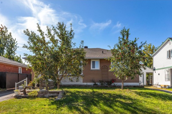 Rear view of the brick house with mature trees in the front yard. - 16 Rue Renaud, Gatineau