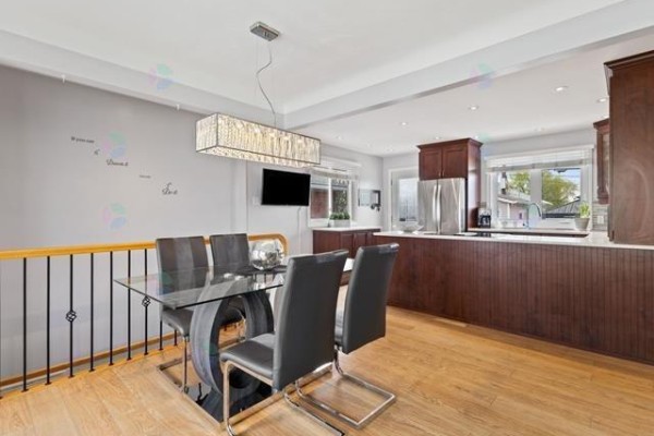 Open concept dining and kitchen area with dark wood cabinets and stainless steel appliances. - 16 Rue Renaud, Gatineau