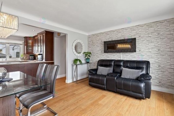 Living room with black leather sofa, fireplace, and a textured accent wall. - 16 Rue Renaud, Gatineau