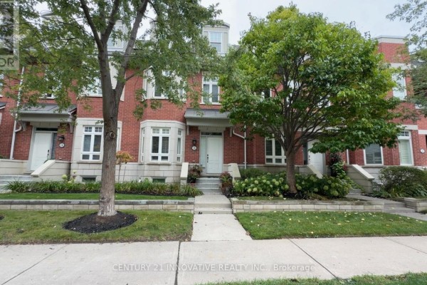Exterior view of the townhouse from the sidewalk with green trees and grass. - 16 St Lawrence Drive, Mississauga