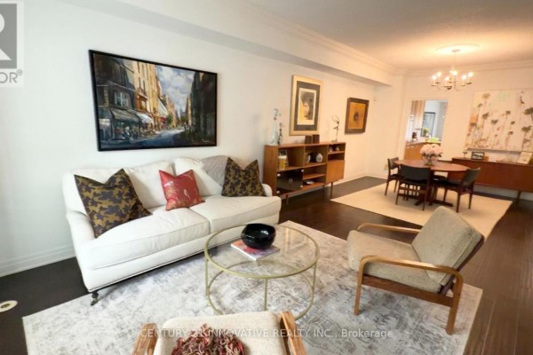 Living room with a cream sofa, glass coffee table, and armchairs. - 16 St Lawrence Drive, Mississauga