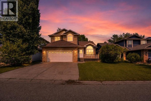 Modern white kitchen with stainless steel appliances, marble backsplash, and light wood laminate flooring. - 16 Sun Harbour Crescent Se, Calgary