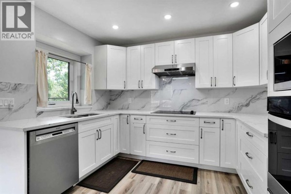Close-up of a white kitchen with marble backsplash, stainless steel dishwasher, sink, and stovetop. - 16 Sun Harbour Crescent Se, Calgary