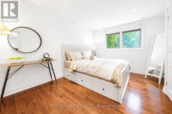 Bedroom with queen bed, hardwood floors, and round mirror - 16 Tuscay Court Markham
