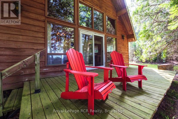 Close-up of two red Adirondack chairs on the wooden deck in front of the cabin. - 16 Youngs Drive, South Bruce Peninsula