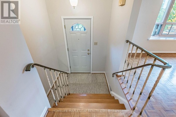 View looking down wooden stairs from the landing towards the front door and living area. - 16 Zealand Road, Toronto