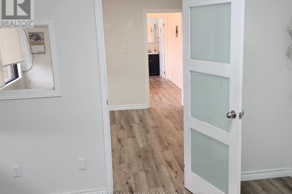View of a doorway with frosted glass panes leading to a hallway with wood-look flooring. - 16/17 - 17075 Leslie Street, Newmarket