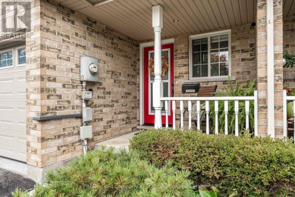 Covered porch of townhouse with white railings and green bushes. - 160 Athlone Crescent, Stratford