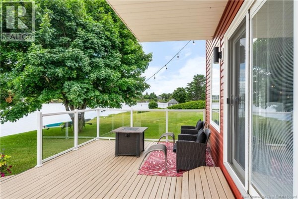 Deck with seating and fire pit, overlooking a calm body of water with trees. - 160 Blanchard Trail, Aldouane