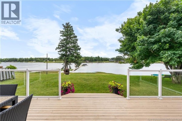 Wooden deck with glass railings and outdoor seating, offering a view of a wide lake. - 160 Blanchard Trail, Aldouane