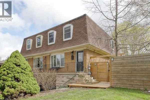 Exterior view of a brick townhouse with a mansard roof and a new wooden fence. - 160 Breckenridge Drive Unit# Upper, Kitchener