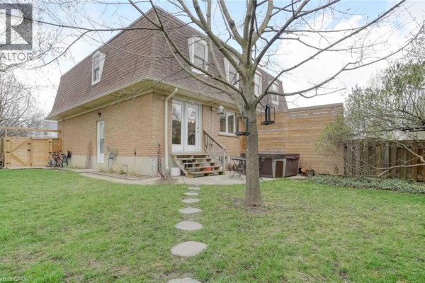 Backyard view of a brick townhouse with a patio, stepping stones, and a hot tub. - 160 Breckenridge Drive Unit# Upper, Kitchener