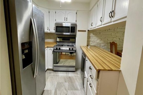 Kitchen with white cabinets, butcher block counters, stainless steel appliances, and a stone backsplash. - 160 Breckenridge Drive Unit# Upper, Kitchener