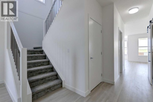 Interior hallway with stairs and doors leading to other rooms. - 160 Copperhead Road Se, Calgary
