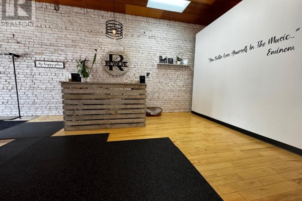 Interior view showing reception desk, white brick wall, and frosted glass partitions. - 160 Main Street W, North Bay