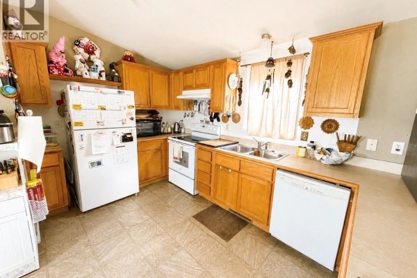 Kitchen with light oak cabinets, white appliances including a dishwasher and refrigerator. - 160 Prairie Sun Court, Swift Current