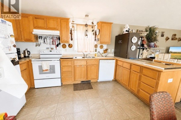 Spacious kitchen with ample wood cabinetry, white appliances, and a large sink area. - 160 Prairie Sun Court, Swift Current