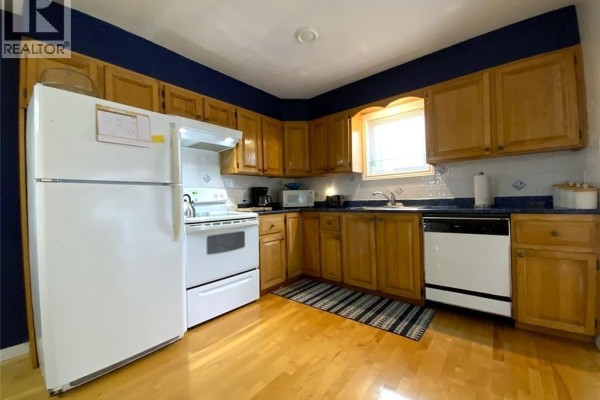 Kitchen with light wood cabinets, white appliances including a refrigerator and stove, and dark blue walls. - 160 Principale Street, Saint Basile