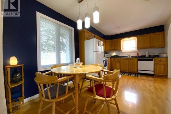 Dining area with a round wooden table and four chairs, adjacent to the kitchen with wood cabinets. - 160 Principale Street, Saint Basile
